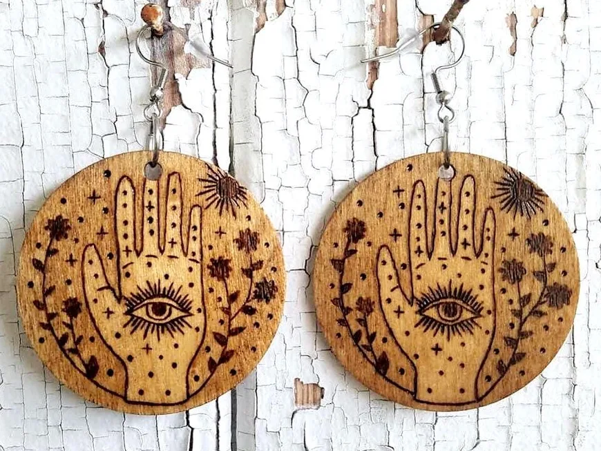 A pair of round wood earrings burned with a witch hand and eye