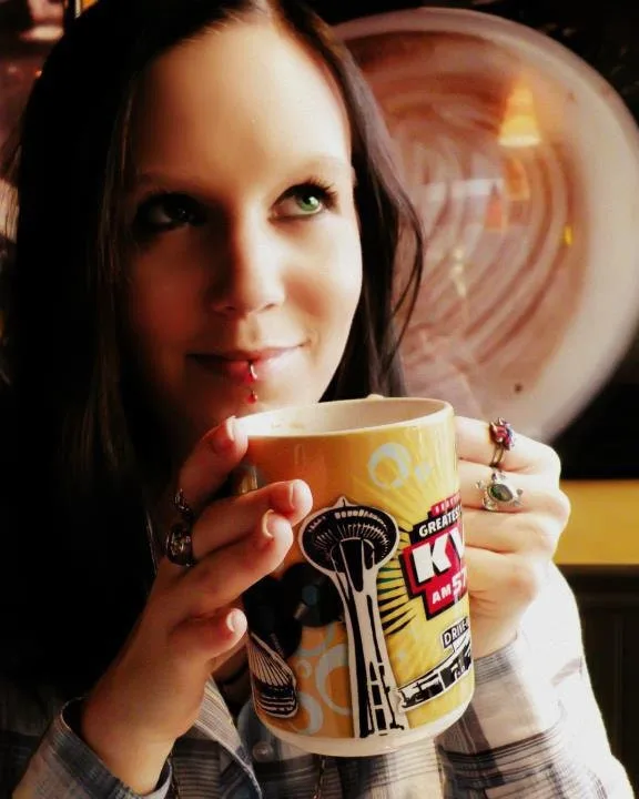 Melissa Calvert, the owner and artist behind Moon, Moth and Torch, holding a coffee mug